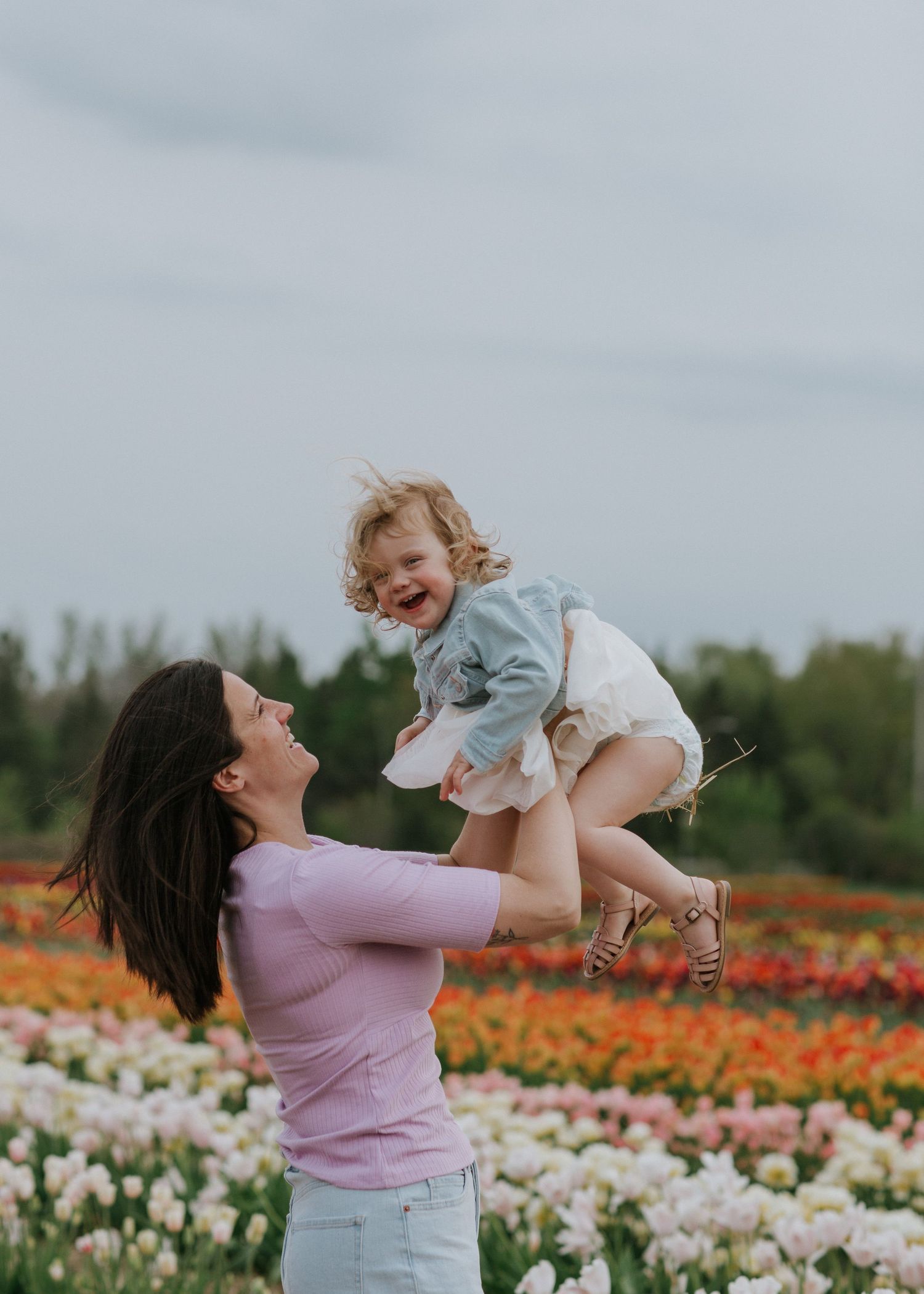 Mother and daughter laughing and having fun in a vibrant tulip field near Ottawa, ON.