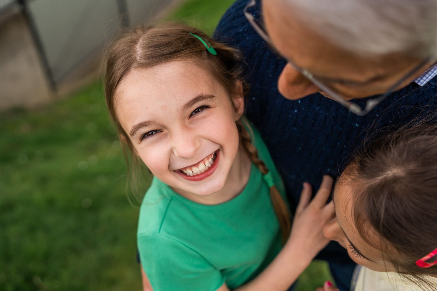 Candid moment of granddaughters smiling while hugging grandfather.