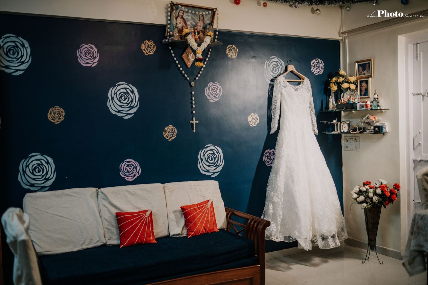 Wedding dress displayed in room with navy blue wall decorated with painted roses.