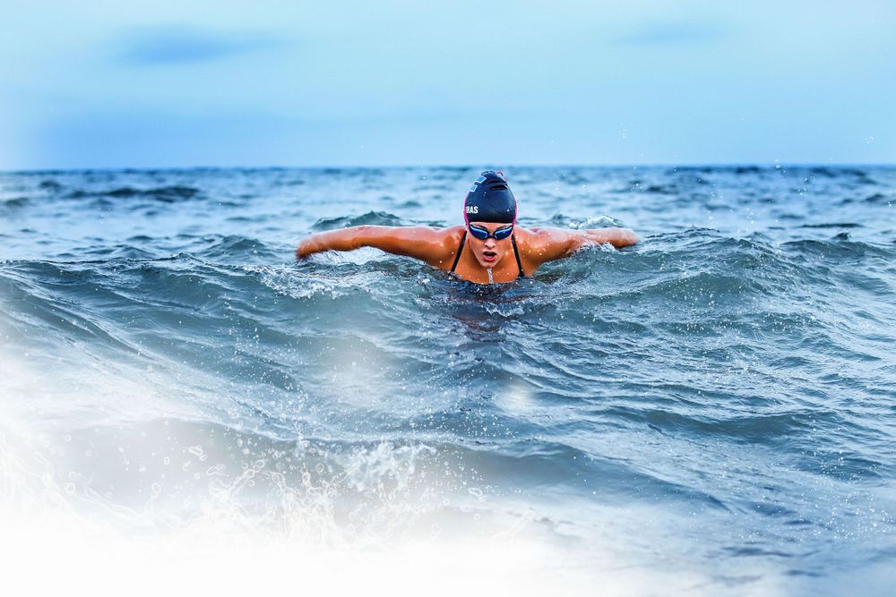 High school senior swimmer doing breast stroke in Lake Superior, Minnesota during photo shoot