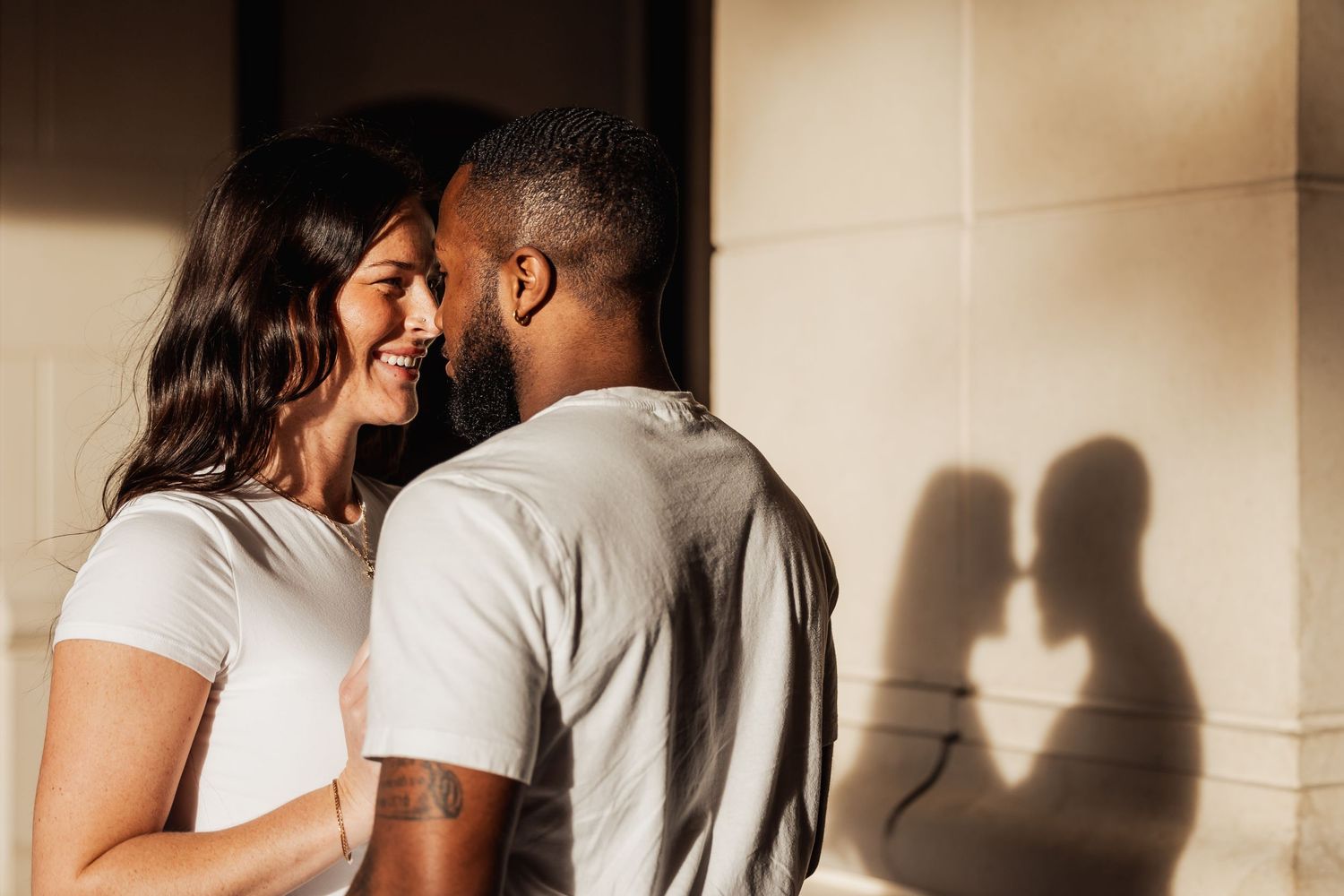 Intimate close-up against a wall creating heart-shaped shadow silhouette.