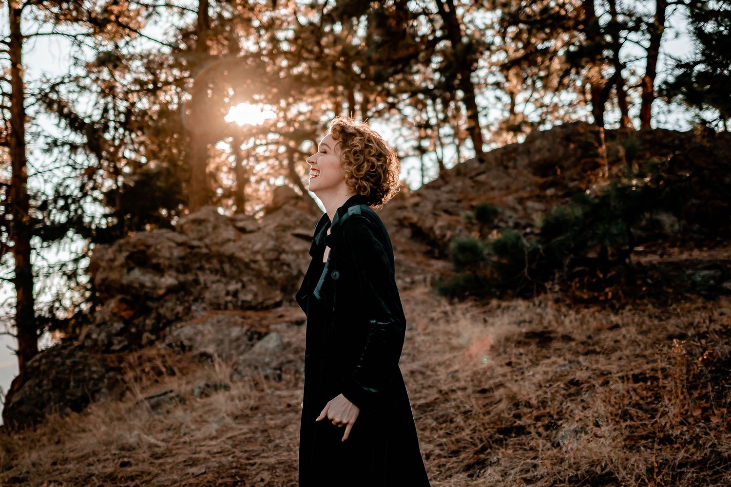 Backlit figure in black clothing stands on hillside during golden hour sunset. Denver Portrait Photography.