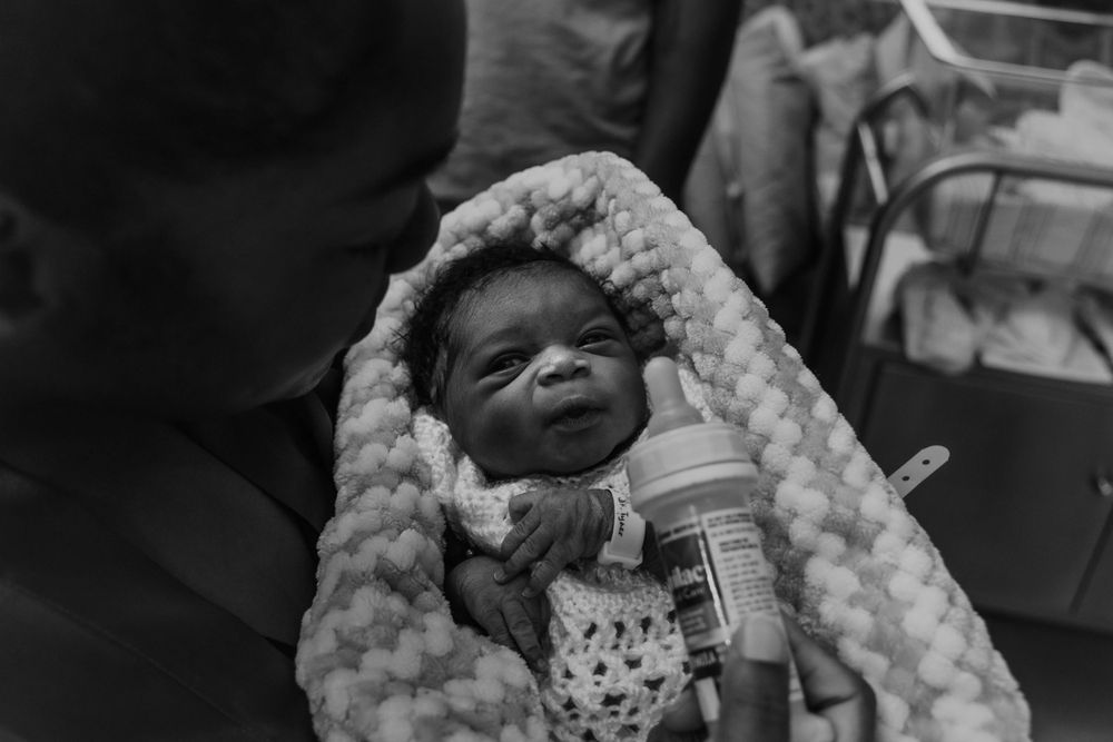 A small baby wrapped in a textured blanket with a bottle nearby.