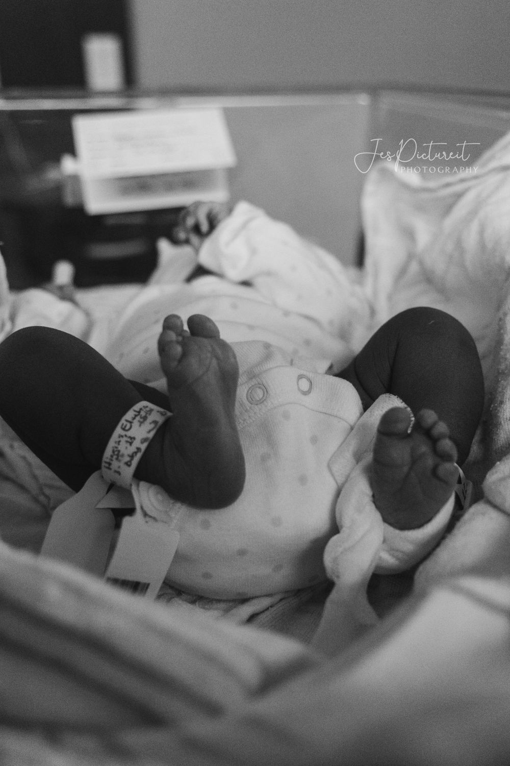 Black and white photo of tiny newborn feet with hospital ID bracelet.
