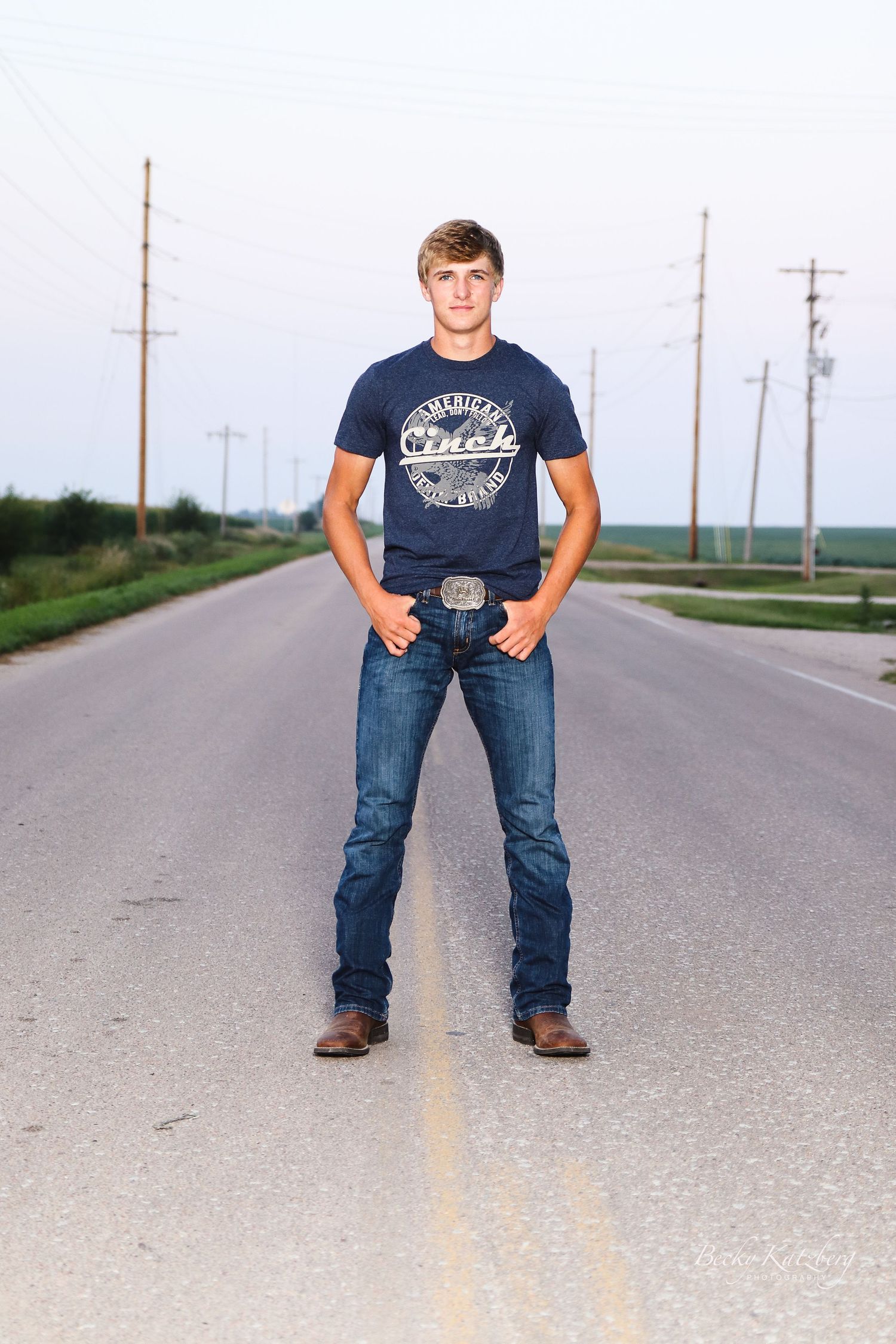 becky katzberg photography senior boy standing on a road at the edge of town