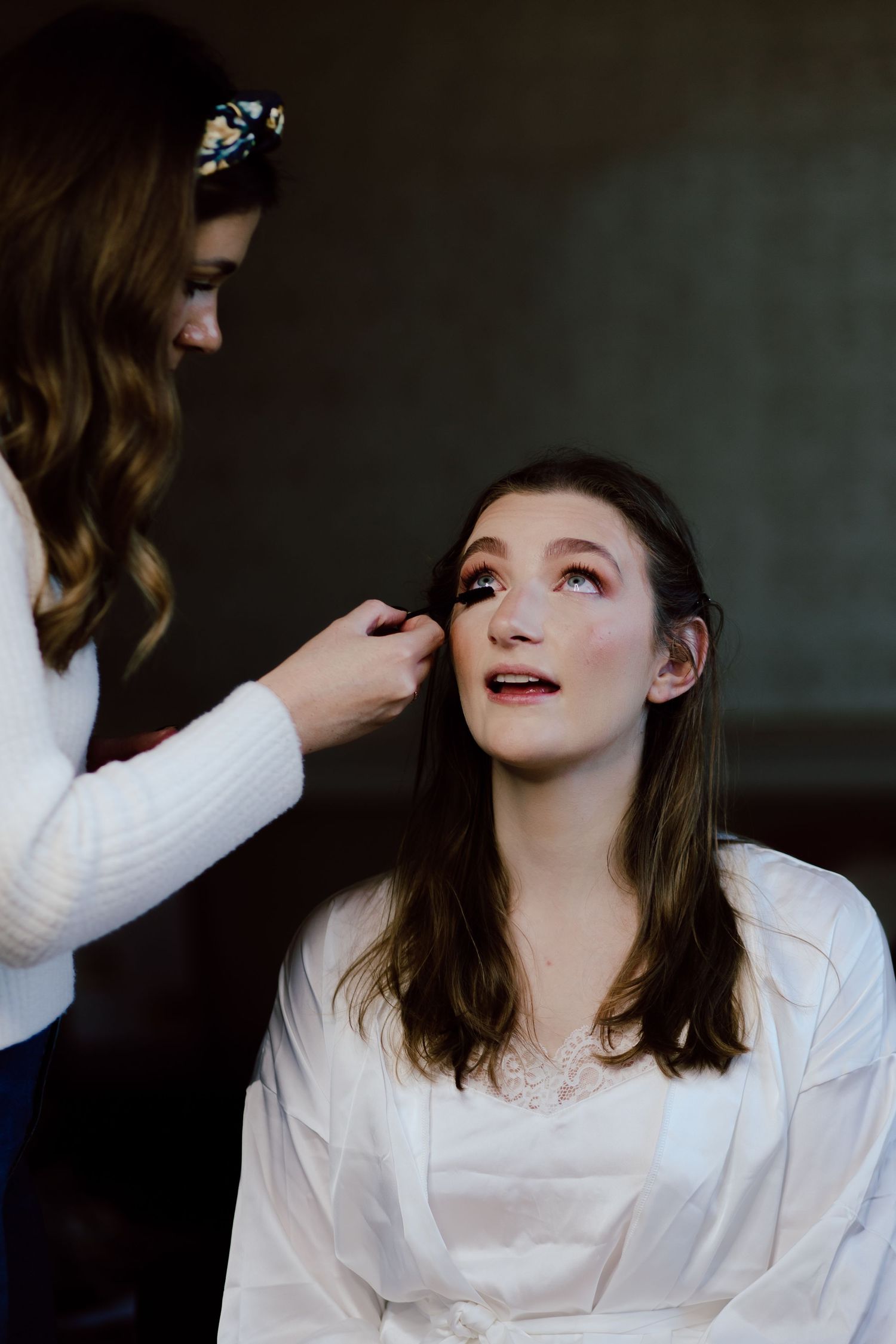 A makeup artist applying final touches to a bride's face during wedding preparation.