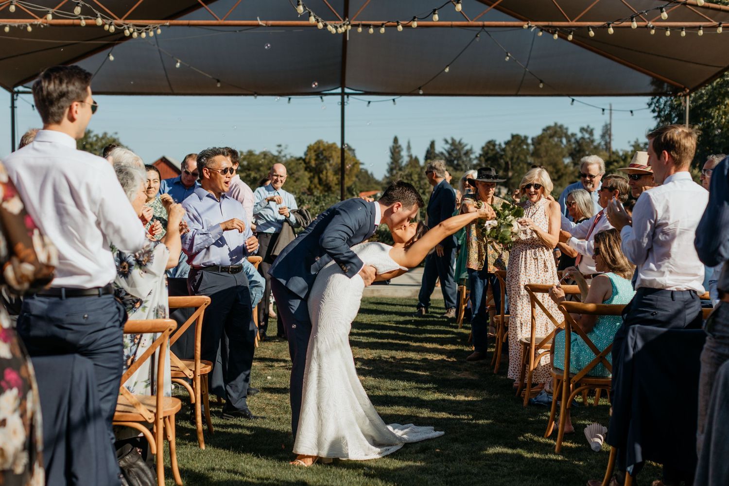 Caucasian male and Asian female give a kiss at the aisle of their wedding at Farmstead in Napa, California