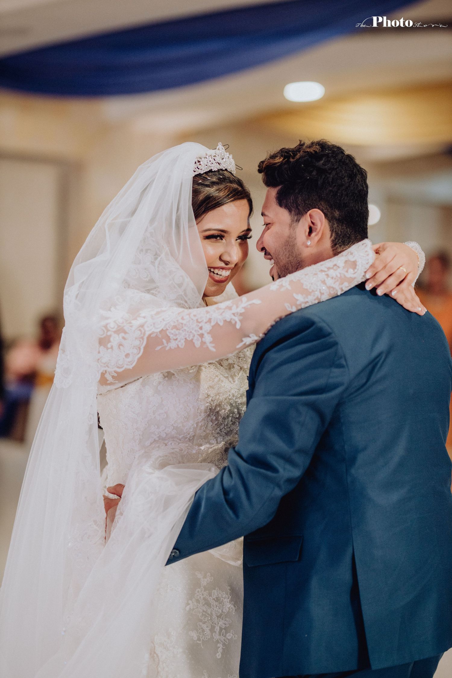 Couple shares romantic first dance at wedding reception with bride wearing elegant lace gown and veil.