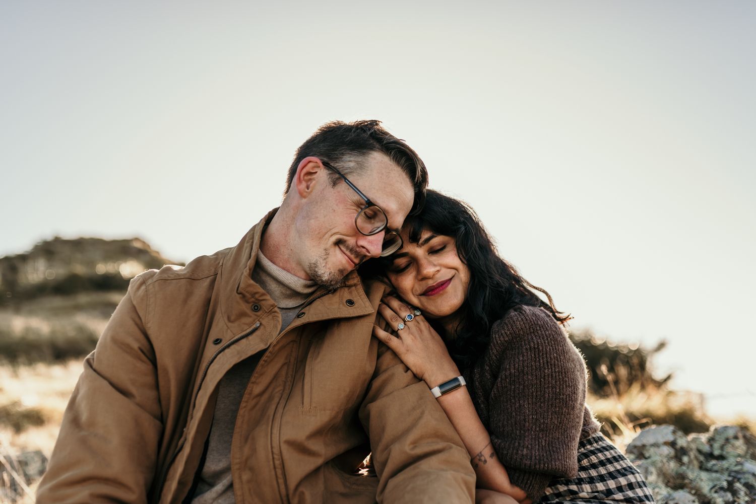 Intimate couple moment shared outdoors against natural backdrop.