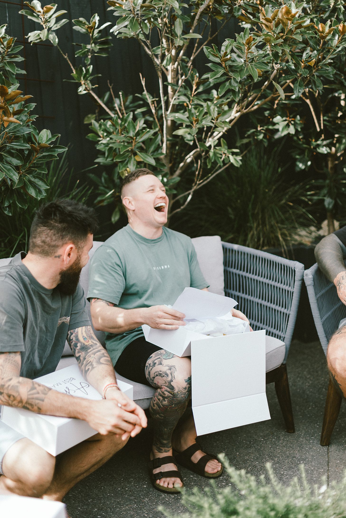 Person laughing while reading papers on outdoor patio with friends.