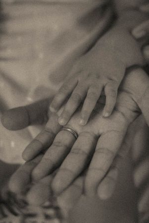 Close-up black and white photo of hands with a wedding ring showing gentle touch and intimacy.