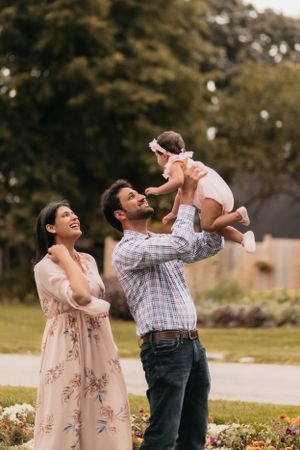 Joyful outdoor family moment in garden with floral dress and plaid shirt.