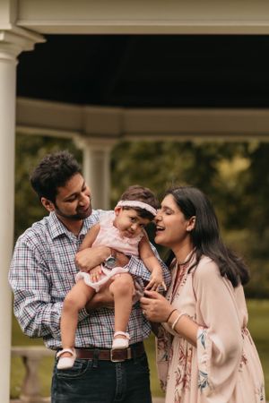Candid family moment under gazebo during outdoor photoshoot.