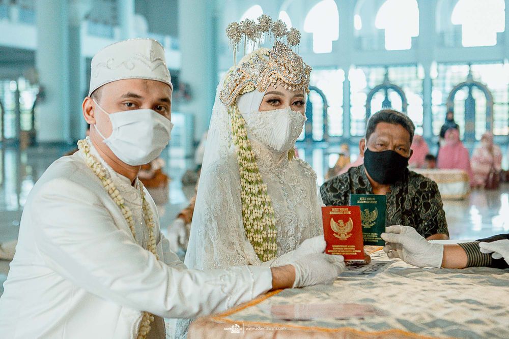 A couple in traditional wedding attire display their identification documents at a table.