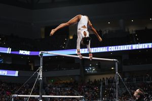 Gymnast performs impressive uneven bars routine during NCAA women's gymnastics championship competition.