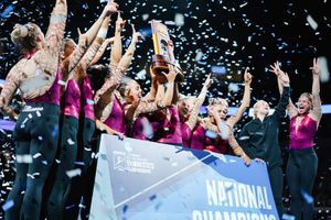 Celebration with confetti at NCAA gymnastics championship event with team banner.
