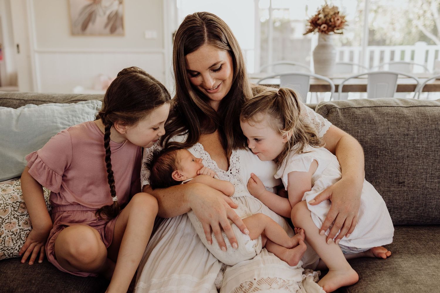 A family gathered on a gray couch sharing a tender moment together.