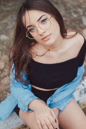 Portrait shot highlighting glasses and denim jacket against textured wall background.