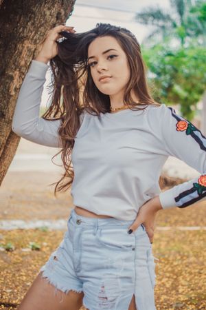 Casual fashion photo showing white long sleeve top and denim shorts in an outdoor setting.