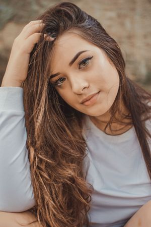 Fashion portrait with flowing hair against earthy background.
