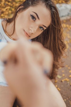 Creative portrait with extended arm reaching toward camera lens.