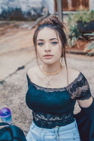 Lifestyle portrait with lace detailed top and denim shorts against outdoor setting.