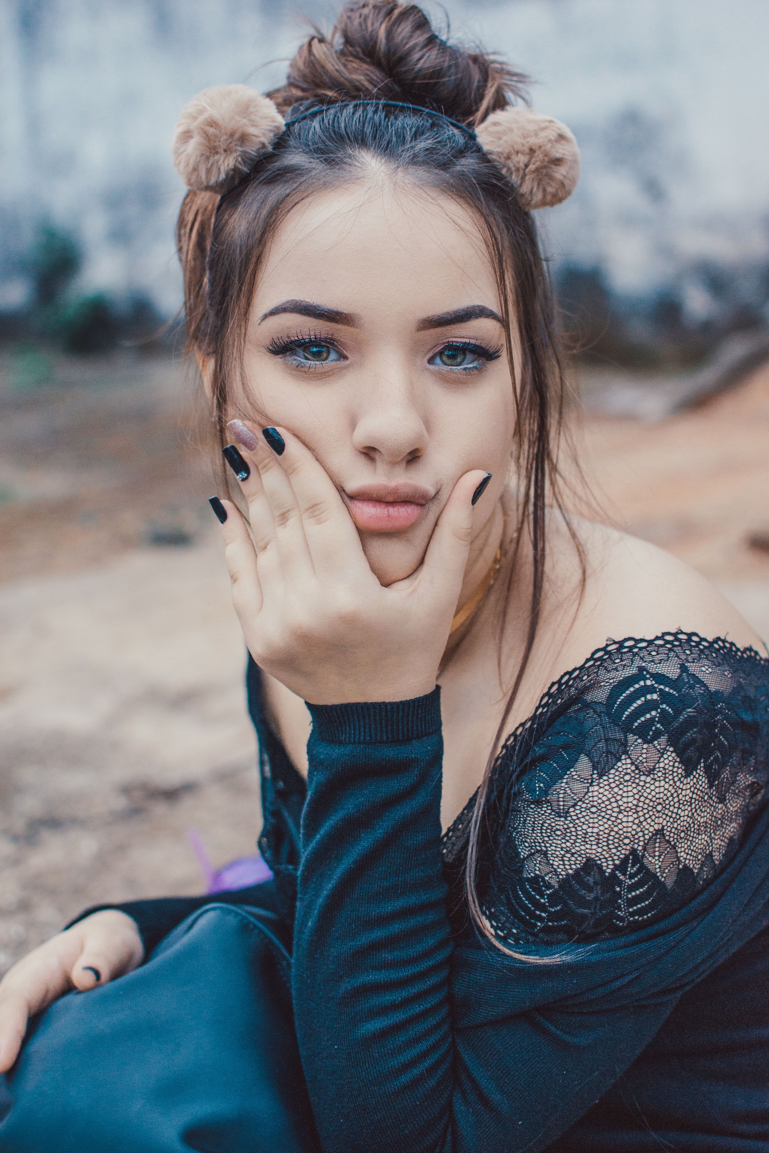 Artistic portrait with pom-pom hair accessories and lace detailed black top.