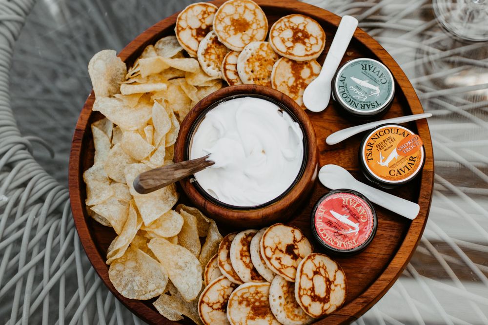 An overhead view of appetizers and dips arranged on a wooden serving platter.