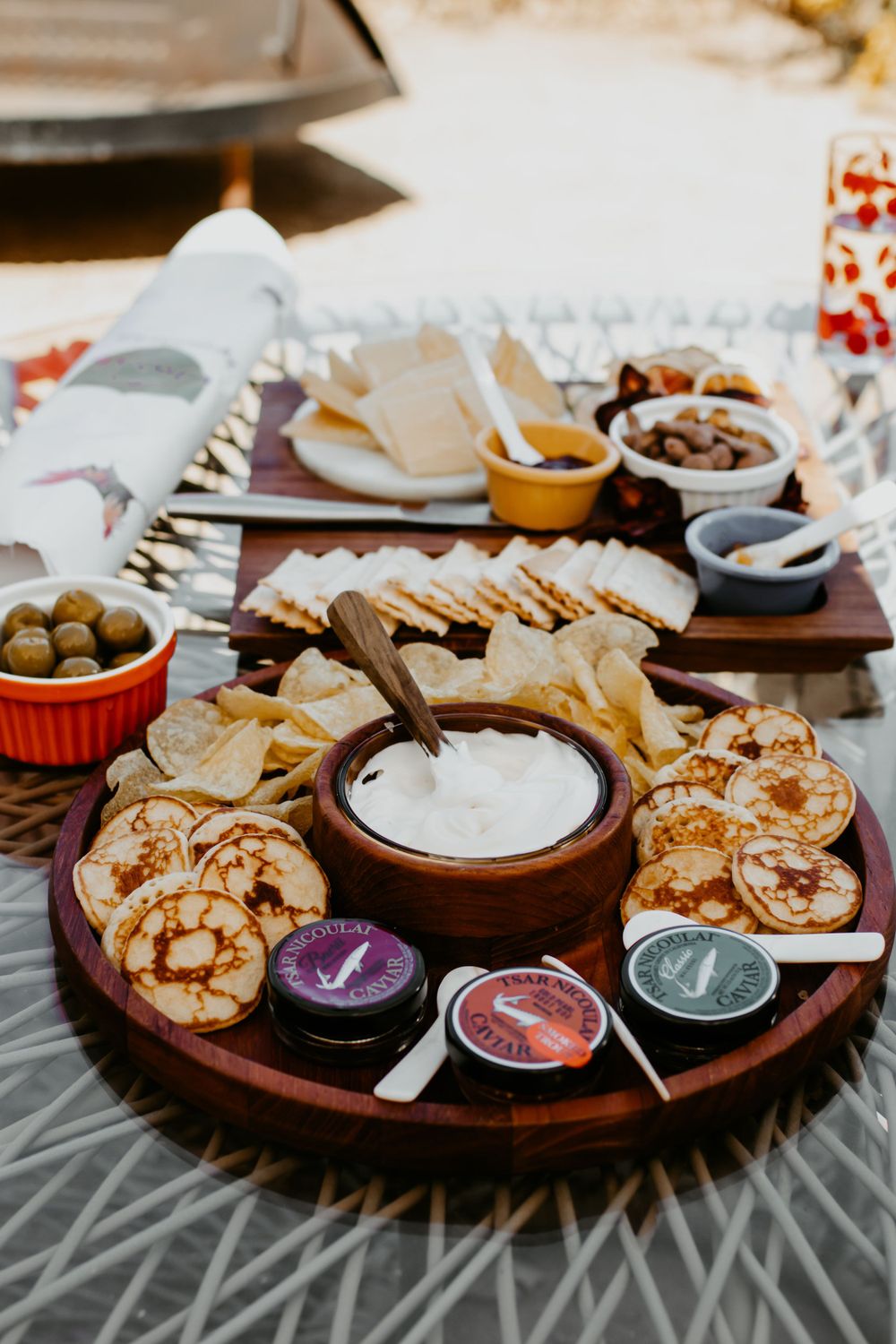 A rustic charcuterie board with crackers, dips, and appetizers arranged on a wooden platter.