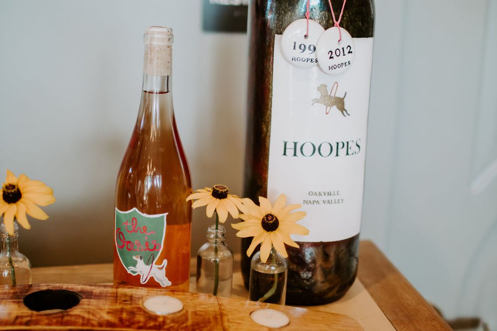 Two wine bottles and sunflowers displayed on a wooden surface for a celebration.
