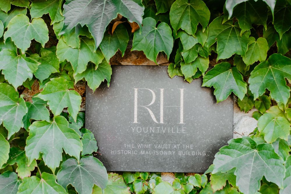 An elegant stone sign with initials surrounded by green ivy leaves.