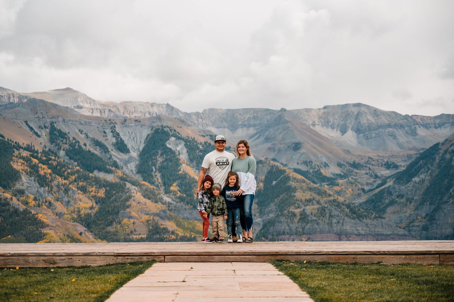 Group poses on viewing platform overlooking majestic mountain landscape.