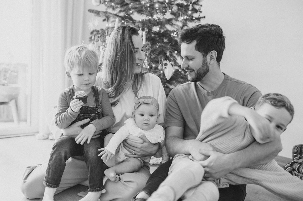 Family gathered together for holiday photo with Christmas tree in background.