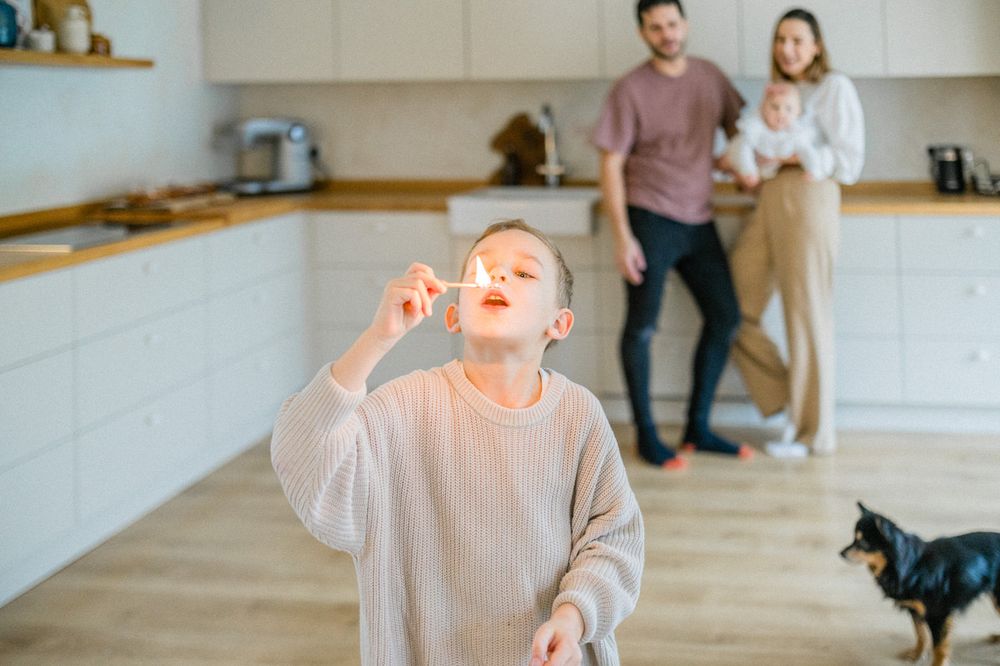 Child playing in modern kitchen while adults and cat watch in background.