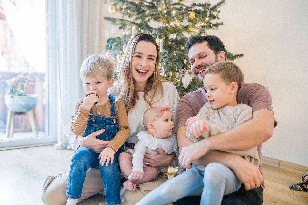 Happy family scene with children sitting together by Christmas tree.