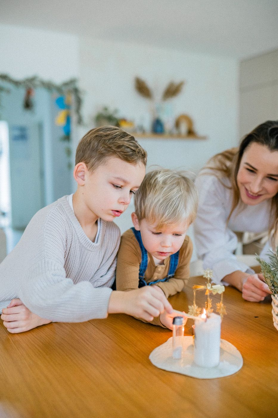Family scene around table focusing on lit candle with home decor in background.