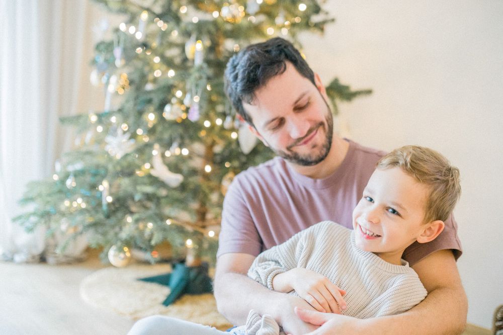 Tender moment shared between two people with decorated Christmas tree in background.