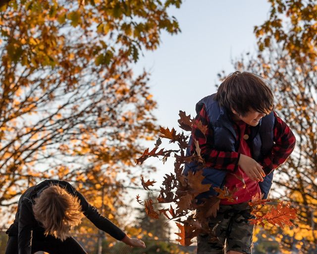 Two boys throw autumn leaves at each other in North Vancouver