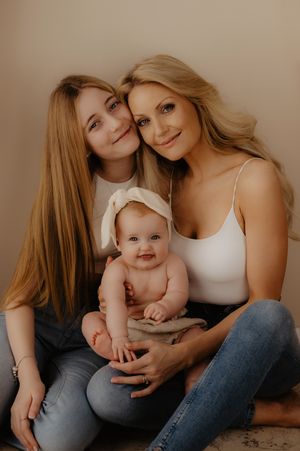 Casual studio portrait of mother and baby in relaxed denim and white tops.