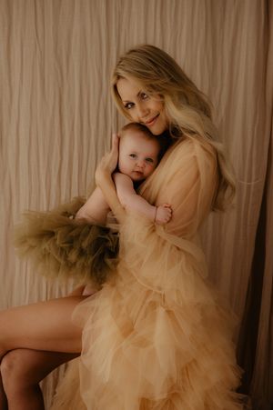Dreamy portrait session featuring parent and baby in flowing champagne-colored tulle dress.