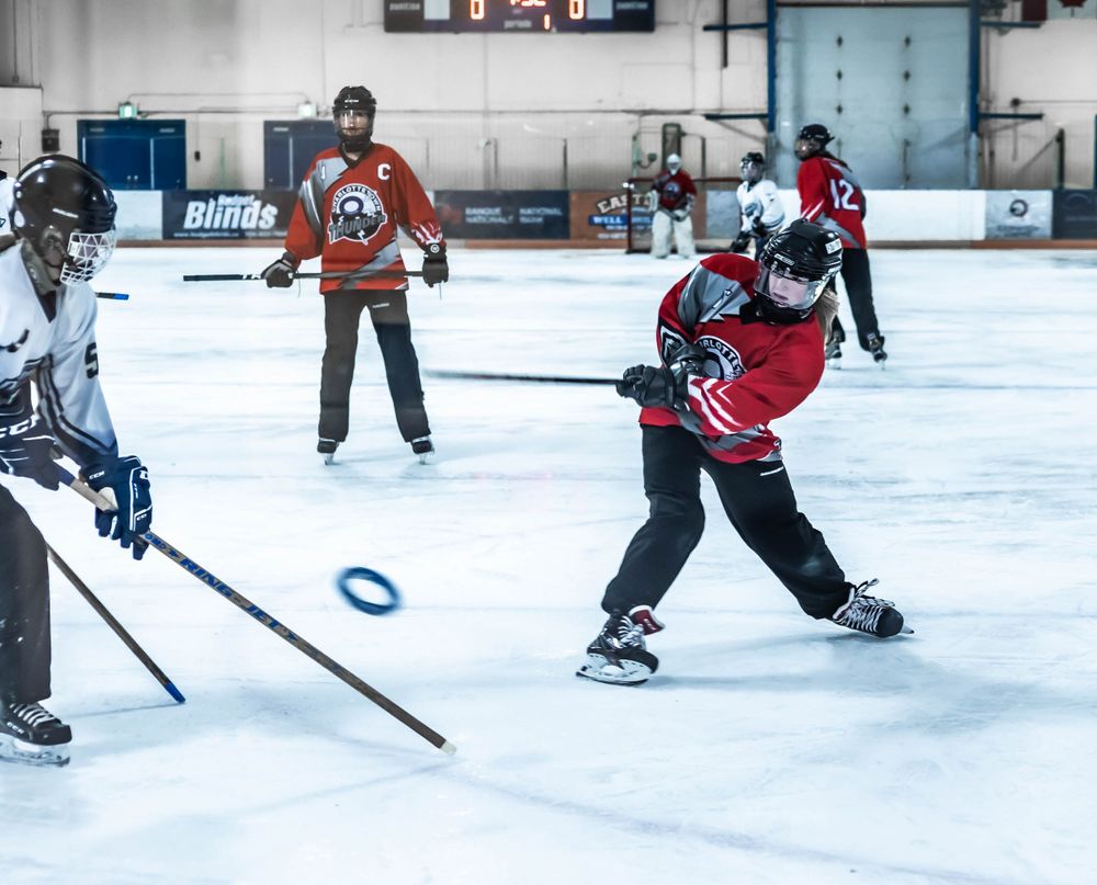Hockey players battle for the puck during a competitive game on indoor ice rink.
