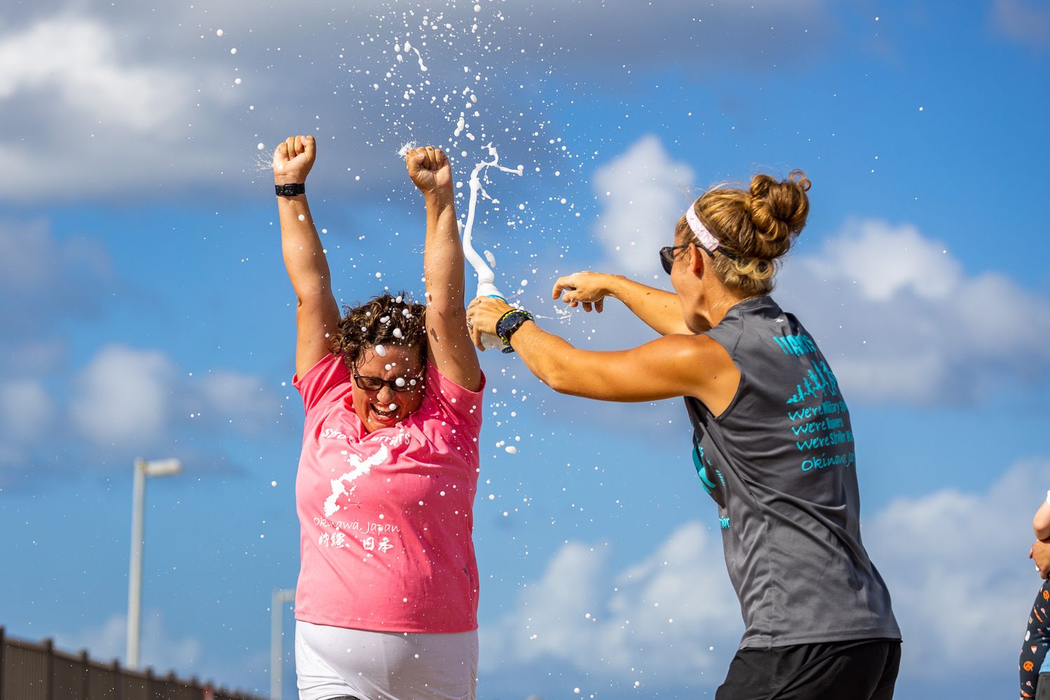 Two people playing and splashing water during an outdoor activity under a cloudy sky.