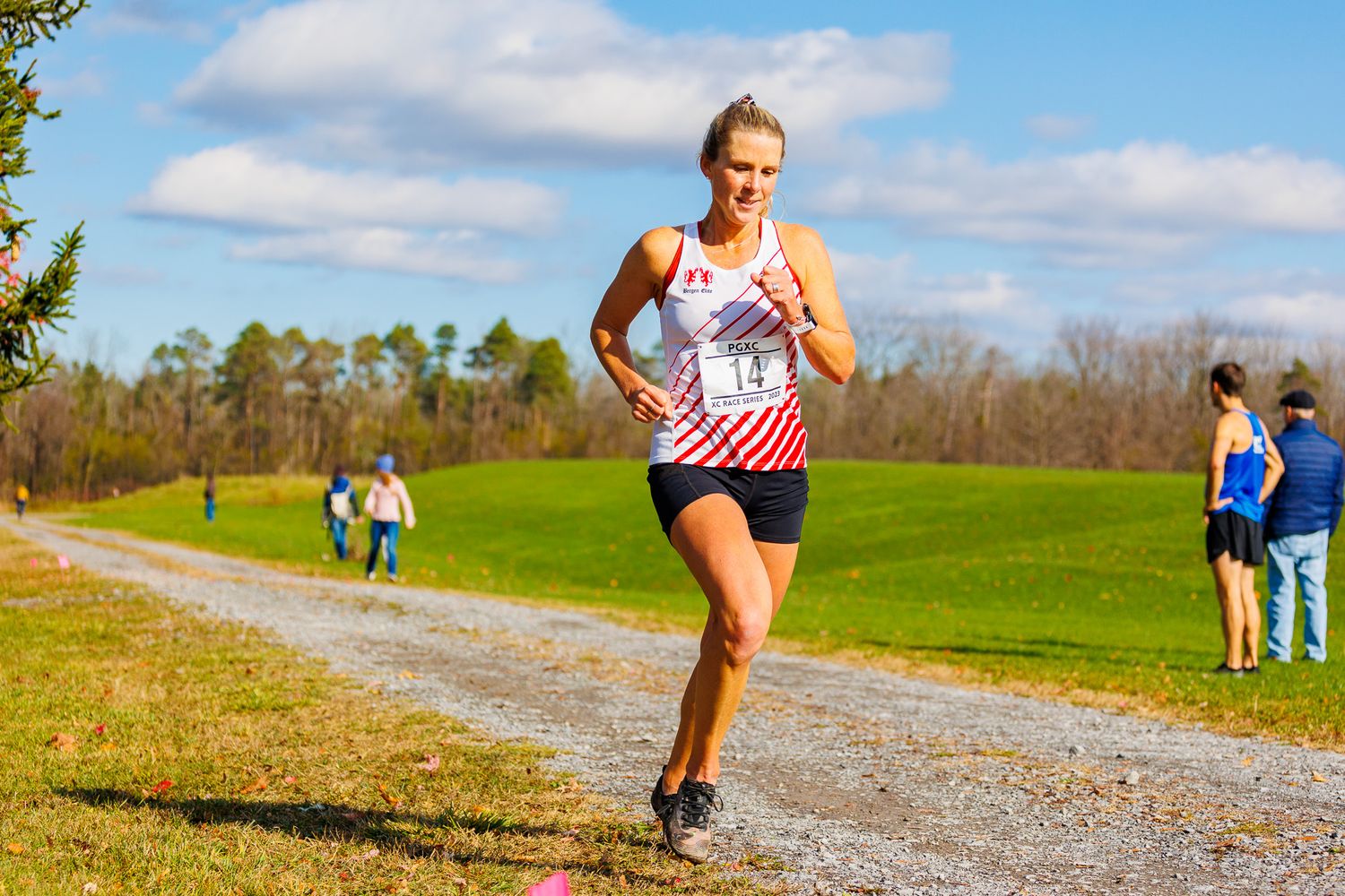 Runner competing in a trail race on a scenic dirt path with blue skies overhead.