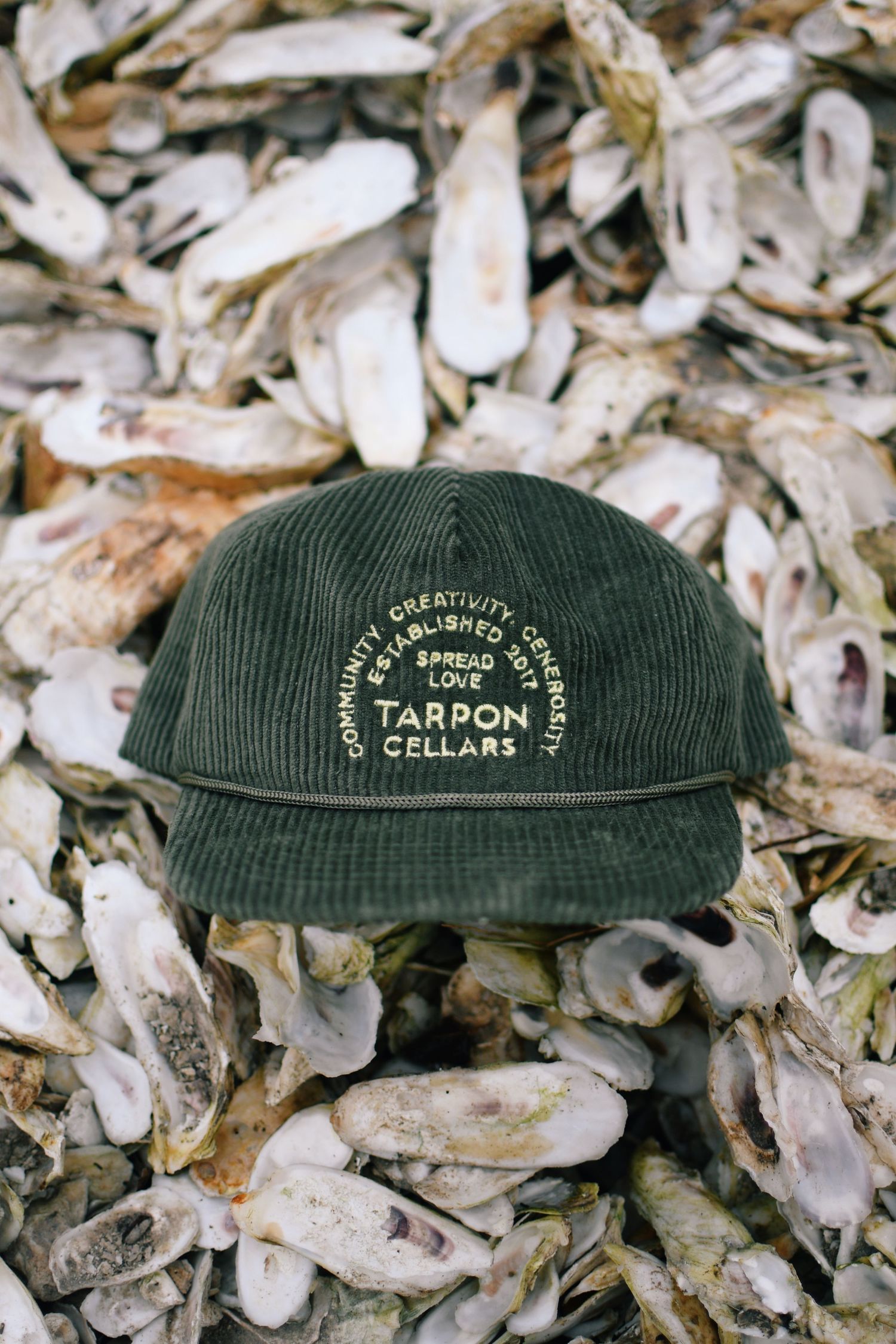 Green corduroy cap with Farron Gallons logo sitting on oyster shells.