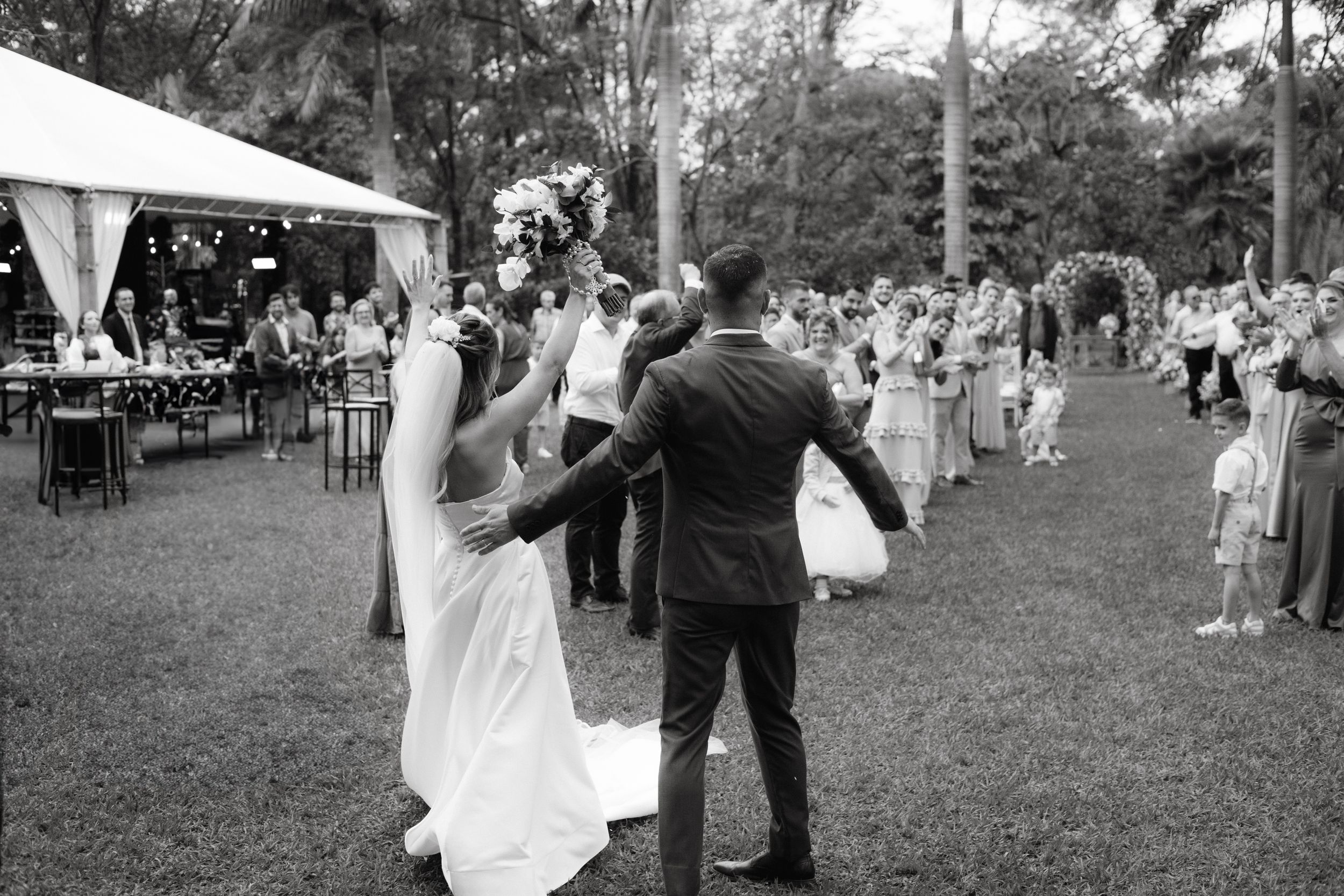 Black and white photo of couple dancing while wedding guests watch at outdoor reception.