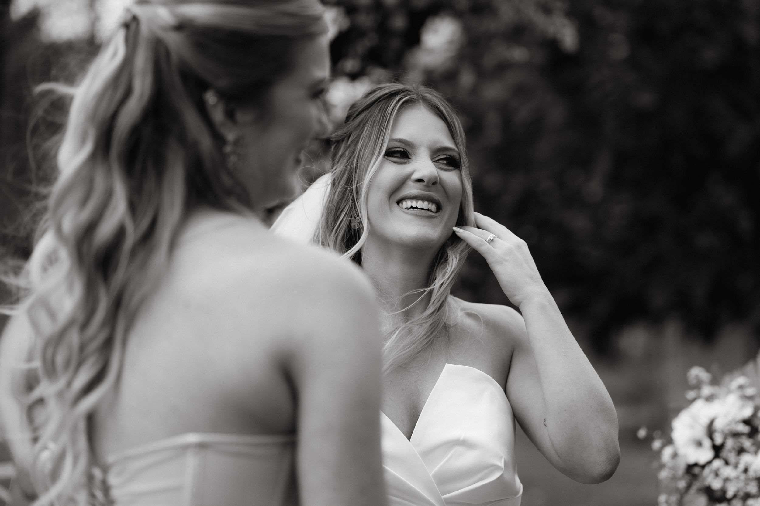 A candid black and white moment captured during an outdoor wedding ceremony.