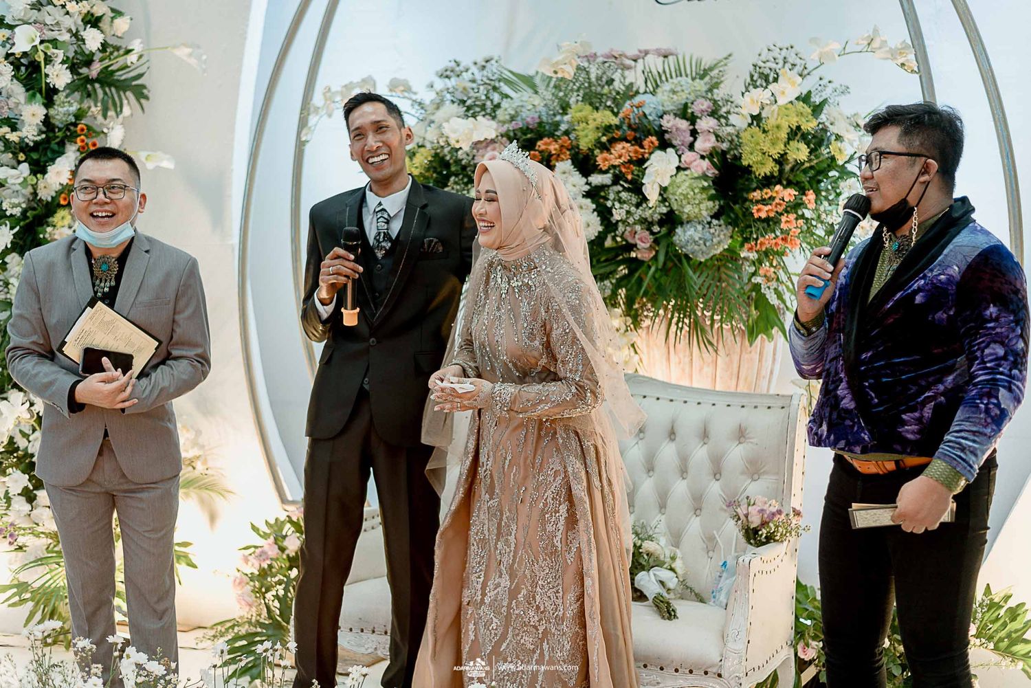 Wedding ceremony with officiants and couple under an elegant floral arch display.