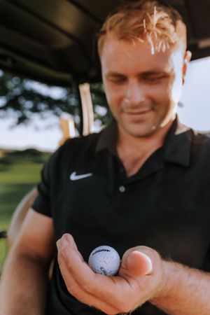 Close-up view of someone holding a golf ball on a sunny day.