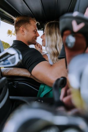 Couple in casual attire sitting close together in a golf cart.