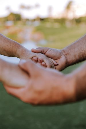Close-up shot of hands holding a ring on a grassy background.